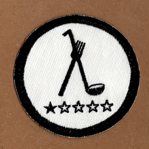 May include: A white embroidered patch with a black outline. The patch features a crossed fork and spoon with five black stars below. The text "*****" is below the fork and spoon.