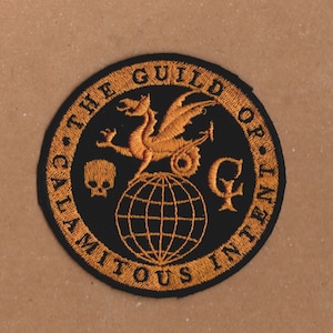 Puede incluir: Un parche bordado en negro y dorado con un dragón, un globo terráqueo y una calavera. El texto alrededor del borde dice "The Guild of Calamitous Intent".