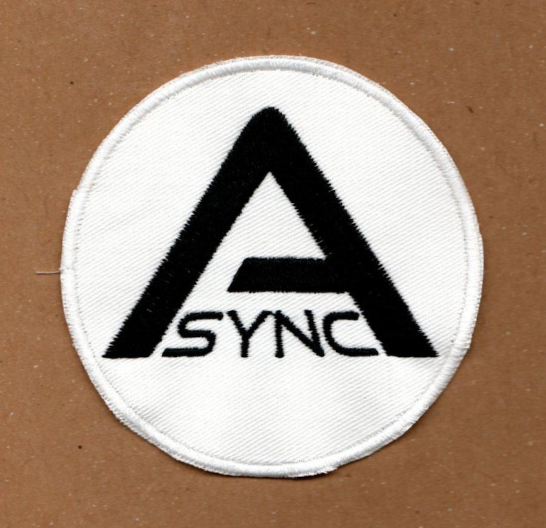 Peut inclure: Un &eacute;cusson brod&eacute; circulaire avec un fond blanc et une bordure noire. Le motif pr&eacute;sente une grande lettre A noire avec le mot SYNC positionn&eacute; horizontalement sur la partie inf&eacute;rieure de la lettre, le tout r&eacute;alis&eacute; en fil noir.