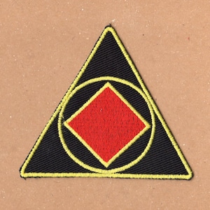 May include: A black triangle patch with a yellow outline. Inside the triangle is a red diamond with a black circle around it.