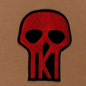May include: Red embroidered skull patch with a black outline and a black letter "K" in the center.