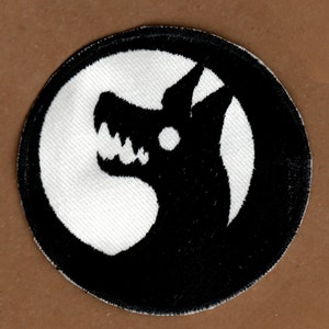 May include: Black and white embroidered patch featuring a snarling wolf head silhouette within a circle.