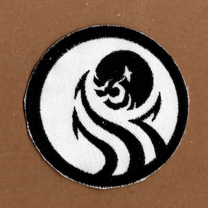 May include: Black and white embroidered patch featuring a stylised wave design. The wave is in the shape of a circle with a black outline.