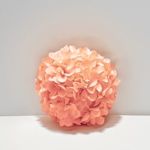 May include: A large, round, peach-colored flower made of paper. The flower is made up of many individual petals.