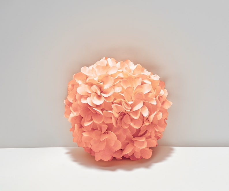 May include: A large, round, peach-colored flower made of paper. The flower is made up of many individual petals.