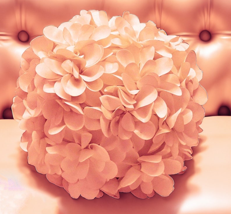 May include: A large, blush-colored flower made of fabric petals. The flower is arranged in a round shape and has a soft, delicate appearance.