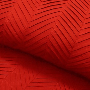 Op de afbeelding: Rode stof met een chevron-patroon. De stof is geplooid en heeft een subtiele glans.