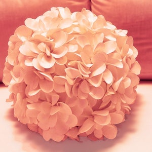 May include: A large, round, peach-colored flower made of fabric petals. The flower is made up of many individual petals that are arranged in a circular pattern.