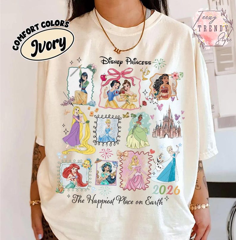May include: Ivory-colored t-shirt featuring Disney Princesses in framed illustrations. The shirt includes the text "Disney Princess" and "The Happiest Place on Earth" with the year "2026". The shirt is labeled "Comfort Colors".