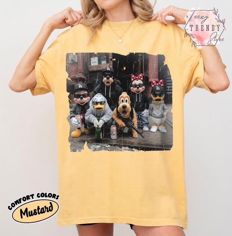 May include: A mustard yellow t-shirt featuring a graphic print of five cartoon characters wearing black baseball caps and sunglasses. The characters are dressed in casual streetwear, including hoodies and jackets, while standing together in an urban setting.