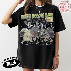 May include: A black t-shirt featuring a graphic print with the text OOGIE BOOGIE BASH and The Spookiest Place on Earth. The design includes illustrations of characters, a castle, a ferris wheel, a moon, and fireworks in various colors.