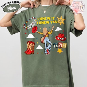 May include: A moss green t-shirt featuring a graphic print with the text I KNEW IT, I KNEW YOU, a character playing a guitar, a beaded bracelet, a red cowboy hat, red cowboy boots, a sheriff badge, clouds, stars, and the text TS5.
