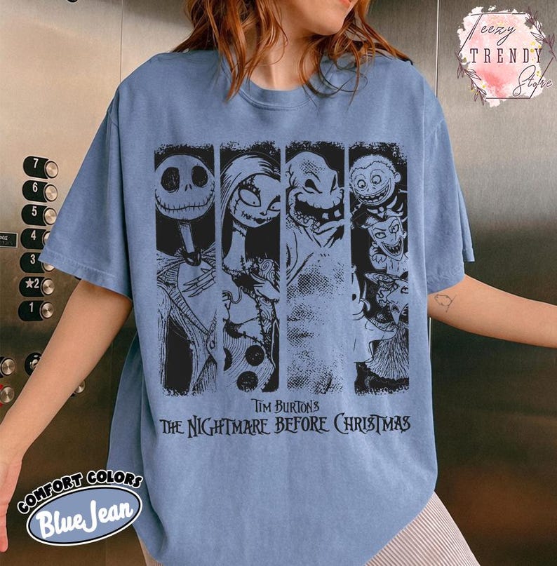 May include: A blue jean coloured t-shirt featuring a black graphic print of characters from Tim Burton's The Nightmare Before Christmas. The design includes four vertical panels showing Jack Skellington, Sally, Oogie Boogie, and Lock, Shock, and Barrel.