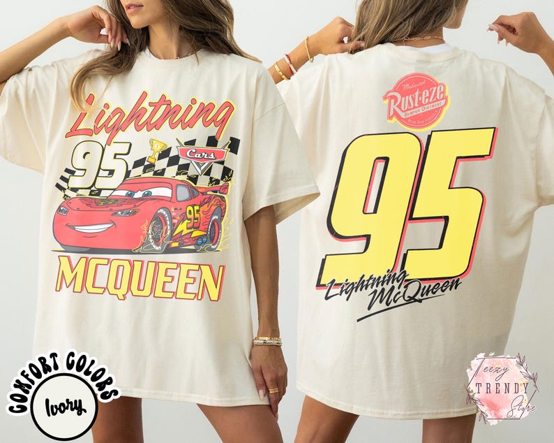 May include: Ivory-colored t-shirt featuring a graphic of Lightning McQueen race car with the number 95. The front design includes the text "Lightning McQueen" and "MCQUEEN". The back of the shirt displays a large number 95 and the text "Lightning McQueen".