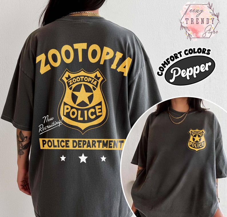 May include: Dark grey t-shirt featuring a yellow "Zootopia Police" badge design on the back and front. The back design includes the text "Zootopia Police Department" and "Now Recruiting!". The shirt is a comfort color.