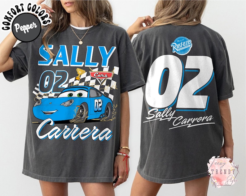 May include: Dark gray t-shirt featuring a blue cartoon car with the text "SALLY 02 Carrera" on the front. The back of the shirt displays a large "02" and "Sally Carrera" text. The shirt has a vintage, distressed look.