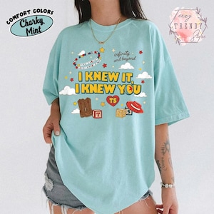 Puede incluir: Una camiseta de color verde menta claro con un estampado gr&aacute;fico que incluye el texto I KNEW IT, I KNEW YOU, infinity and beyond y YOU'VE GOT A FRIEND IN ME. El dise&ntilde;o presenta ilustraciones de botas vaqueras, un sombrero rojo, bloques y estrellas.