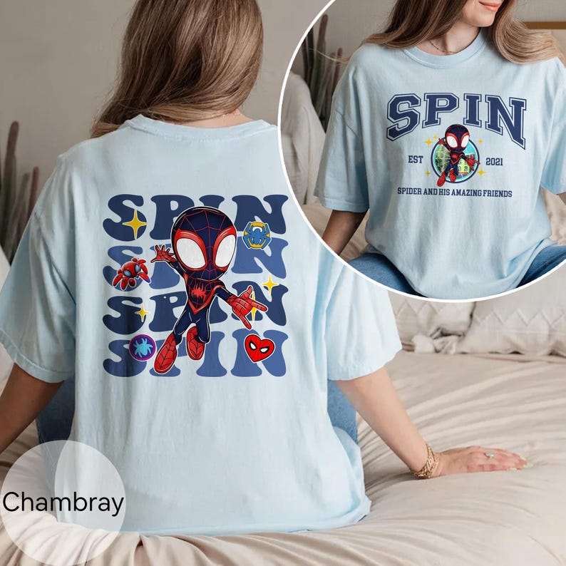 Puede incluir: Camiseta azul claro con un gr&aacute;fico de dibujos animados de un superh&eacute;roe y la palabra "SPIN". La parte posterior de la camiseta tiene una versi&oacute;n m&aacute;s grande del mismo dise&ntilde;o. La camiseta tambi&eacute;n tiene el texto "SPIDER AND HIS AMAZING FRIENDS".