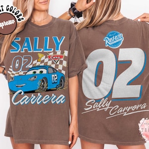 May include: Brown t-shirt featuring a blue cartoon car with the text "SALLY 02 Carrera" in blue and white. The back of the shirt displays a large "02" and "Sally Carrera" with a "Rusteze" logo.