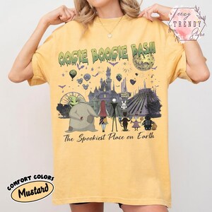 May include: A mustard yellow short-sleeve t-shirt featuring a graphic print with the text OOGIE BOOGIE BASH and The Spookiest Place on Earth. The design includes a castle, a moon, and various characters from The Nightmare Before Christmas.