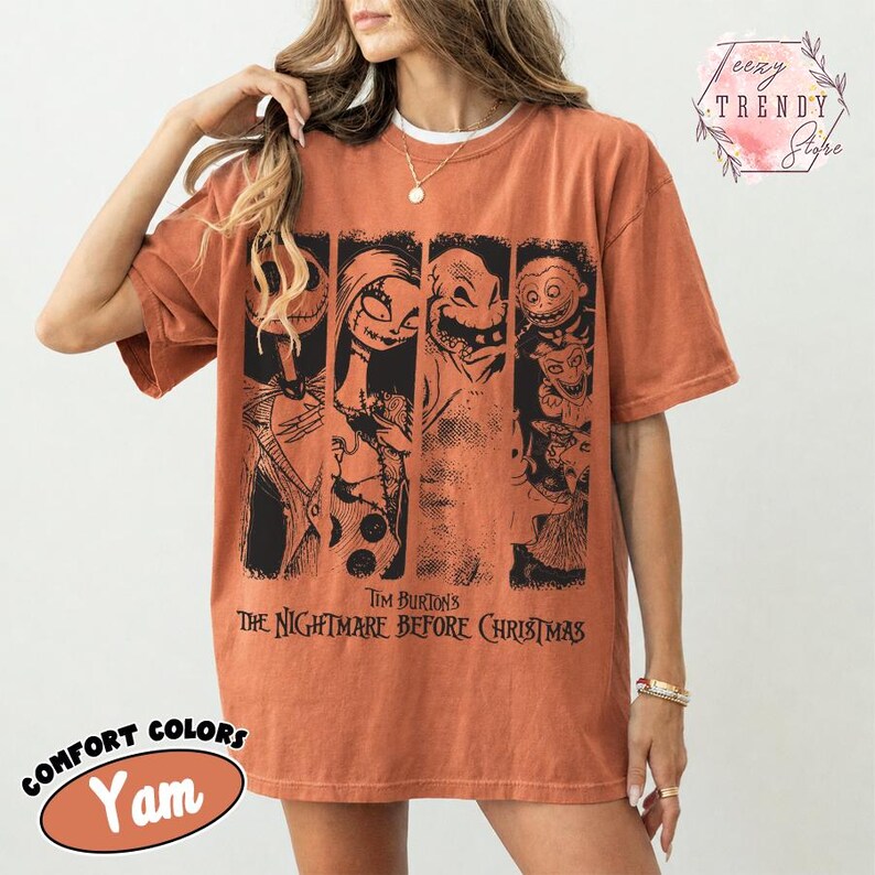 May include: A rust-coloured short-sleeve t-shirt featuring a black graphic print of characters from Tim Burton's The Nightmare Before Christmas. The design is divided into four vertical panels, each showcasing a different character from the film.