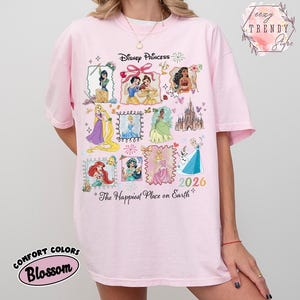 May include: A light pink t-shirt featuring Disney Princesses in framed illustrations. The shirt has the text "Disney Princess" at the top and "The Happiest Place on Earth" at the bottom, with the year "2026". The shirt is made of Comfort Colors Blossom fabric.