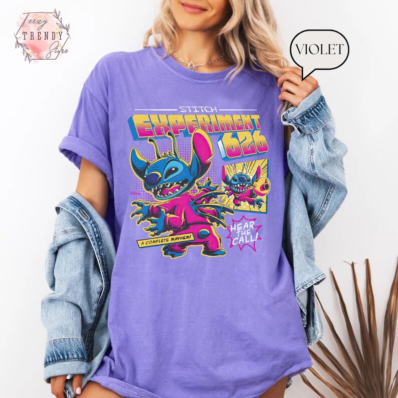 Pode incluir: Camiseta violeta com um gr&aacute;fico de Stitch de Lilo & Stitch. O design inclui o texto "Stitch Experiment 626" e "Hear the Call". O personagem de desenho animado &eacute; retratado em azul e rosa.
