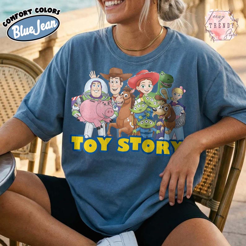 Puede incluir: Camiseta azul vaquero Comfort Colors con un gr&aacute;fico de personajes de Toy Story. El dise&ntilde;o incluye a Buzz Lightyear, Woody, Jessie y otros personajes de la pel&iacute;cula animada. Las palabras "TOY STORY" est&aacute;n impresas en amarillo.