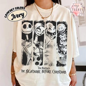May include: An ivory short-sleeve t-shirt featuring a black graphic print of characters from Tim Burton's The Nightmare Before Christmas. The design includes four vertical panels showing Jack Skellington, Sally, Oogie Boogie, and Lock, Shock, and Barrel.