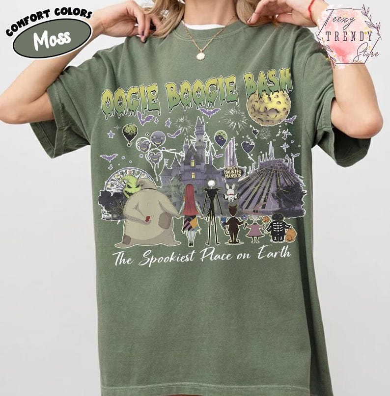 May include: A moss green t-shirt featuring a graphic print with the text OOGIE BOOGIE BASH and The Spookiest Place on Earth. The design includes illustrations of characters from The Nightmare Before Christmas, a castle, a moon, and fireworks.