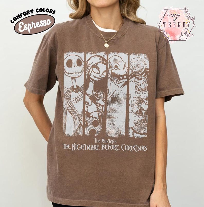 May include: An espresso brown short-sleeve t-shirt featuring a white graphic print of characters from Tim Burton's The Nightmare Before Christmas. The design includes four vertical panels displaying Jack Skellington, Sally, Oogie Boogie, and Lock, Shock, and Barrel.
