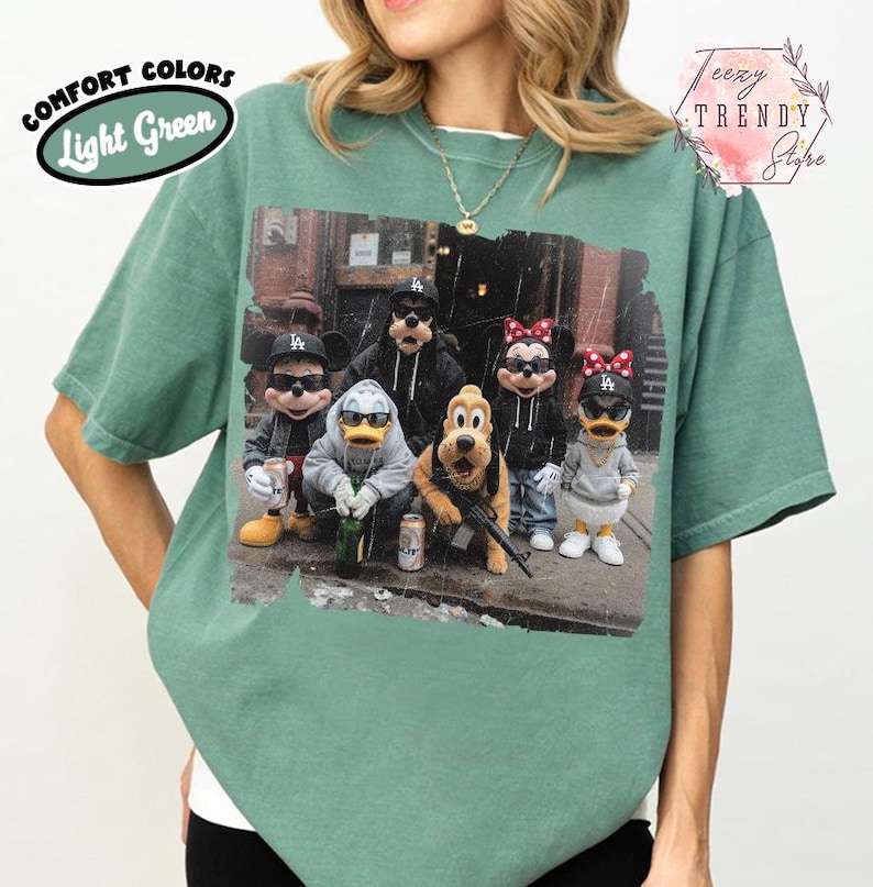 May include: A light green t-shirt featuring a graphic print of cartoon characters wearing sunglasses and streetwear, including hats and hoodies. The text COMFORT COLORS Light Green appears in the top left, and the text Teezy TRENDY Store is in the top right.