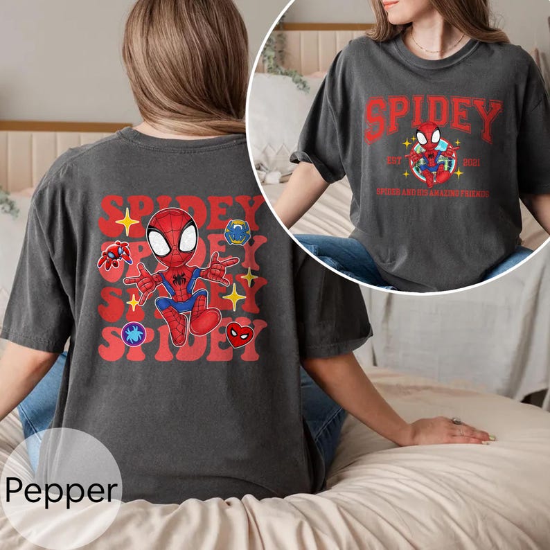Puede incluir: Camiseta color pimienta con un gr&aacute;fico de Spidey. La parte delantera de la camiseta muestra la palabra "Spidey" en rojo, con una ilustraci&oacute;n de dibujos animados de Spider-Man. La parte trasera de la camiseta tiene un gr&aacute;fico de Spidey m&aacute;s grande con ilustraciones de personajes adicionales.