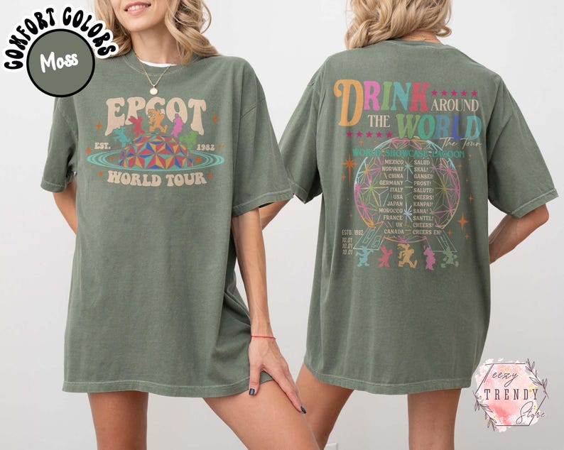 May include: Moss green t-shirt with front and back graphics. The front graphic says "EPCOT World Tour" with a colorful design. The back graphic says "Drink Around The World" with a globe and country names.