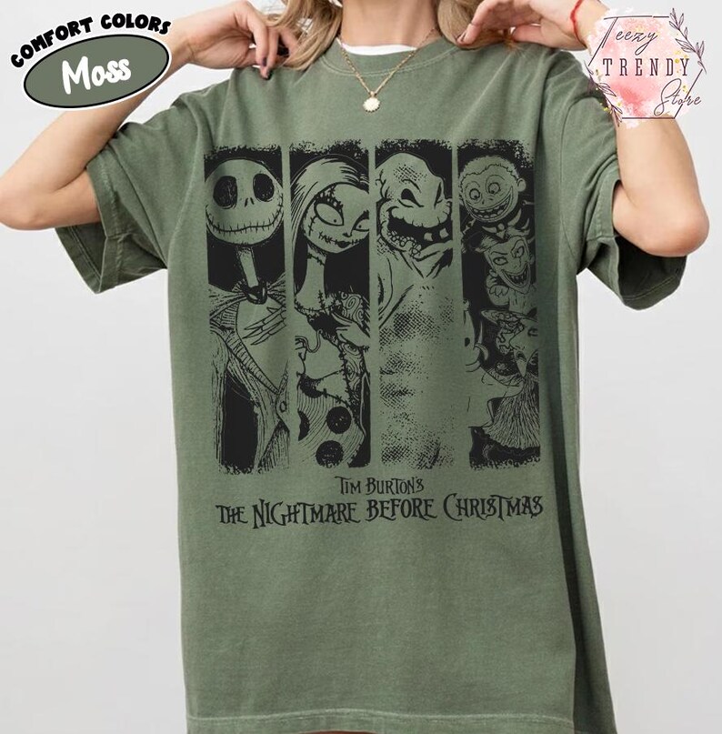 May include: A moss green short-sleeve t-shirt featuring a black graphic print of characters from Tim Burton's The Nightmare Before Christmas. The design includes four vertical panels showing Jack Skellington, Sally, Oogie Boogie, and Lock, Shock, and Barrel.