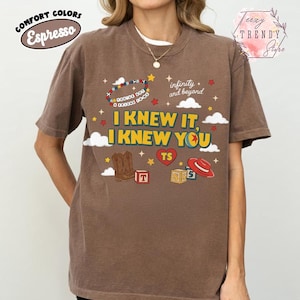 Puede incluir: Una camiseta de manga corta color marr&oacute;n espresso con un estampado gr&aacute;fico que incluye el texto I KNEW IT, I KNEW YOU, infinity and beyond y YOU'VE GOT A FRIEND IN ME. El dise&ntilde;o incluye una pulsera de cuentas, botas vaqueras, bloques y un sombrero rojo.