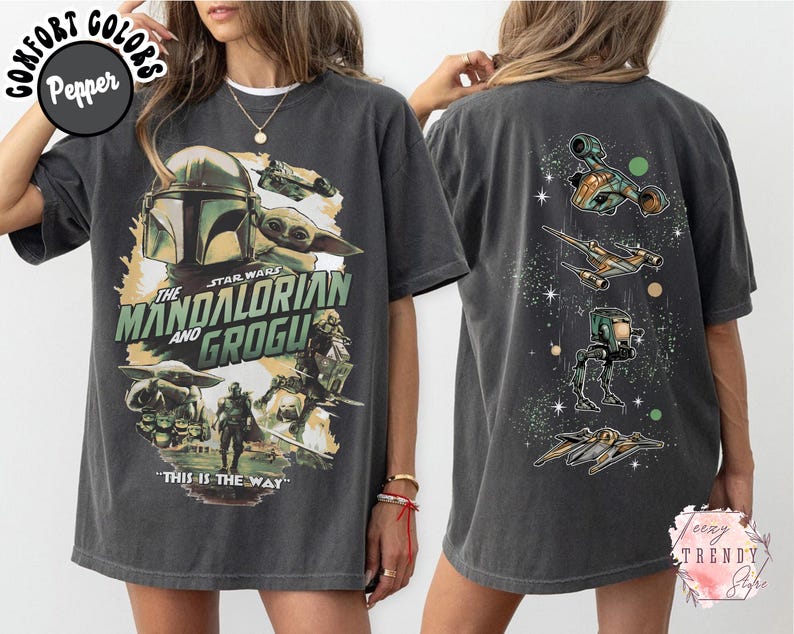 K&ouml;nnte beinhalten: Ein anthrazitfarbenes Kurzarm-T-Shirt mit einem Frontdruck von The Mandalorian und Grogu sowie dem Text "The Mandalorian and Grogu" und "This is the way". Die R&uuml;ckseite zeigt verschiedene Star Wars-Raumschiffe und ein L&auml;ufer-Fahrzeug.