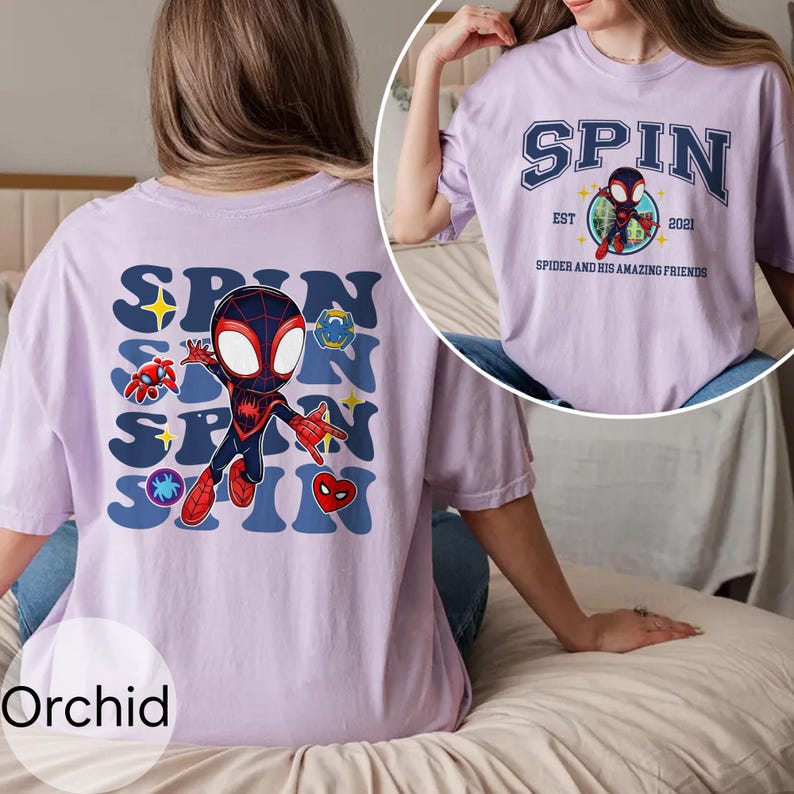 Puede incluir: Camisetas de color orqu&iacute;dea con un gr&aacute;fico de un Spider-Man de dibujos animados. La parte delantera de la camiseta tiene la palabra "SPIN" en una fuente estilizada, con un personaje de Spider-Man en el centro. La parte trasera de la camiseta tiene la palabra "SPIN" repetida con gr&aacute;ficos de Spider-Man.