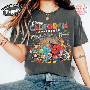 以下が含まれることがあります： 「ディズニー・カリフォルニア・アドベンチャー」の文字と、ディズニーキャラクターのカラフルなグラフィックが特徴のダークグレーTシャツ。 ゆったりとしたフィット感の、Comfort Colorsブランドのシャツです。