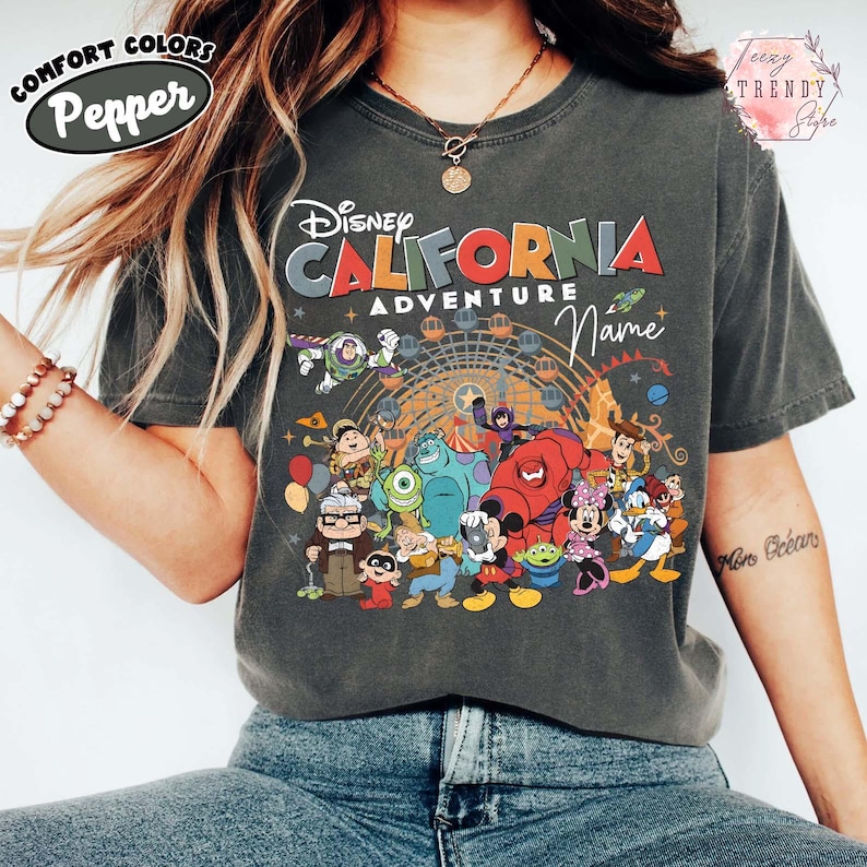 以下が含まれることがあります： 「ディズニー・カリフォルニア・アドベンチャー」の文字と、ディズニーキャラクターのカラフルなグラフィックが特徴のダークグレーTシャツ。 ゆったりとしたフィット感の、Comfort Colorsブランドのシャツです。
