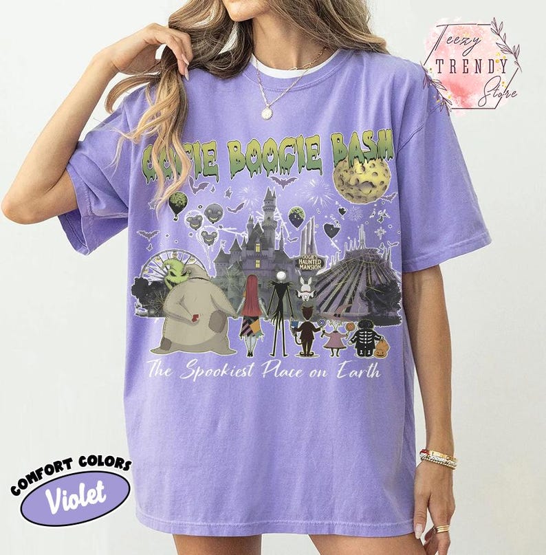 May include: A violet short-sleeve t-shirt featuring a graphic print with the text Oogie Boogie Bash and The Spookiest Place on Earth. The design includes illustrations of various characters, a castle, a moon, and fireworks in a dark theme.