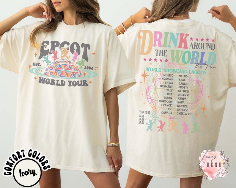 May include: Ivory-colored t-shirt featuring the text "EPCOT WORLD TOUR" with a colorful graphic of a geodesic sphere and characters. The back of the shirt reads "DRINK AROUND THE WORLD" with a list of countries and phrases.
