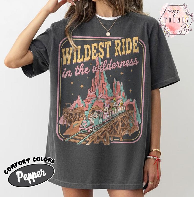 Może przedstawiać: Ciemnoszara koszulka z grafiką w stylu vintage przedstawiającą pociąg z Myszka Miki i Minnie, napisem "Wildest Ride in the Wilderness" oraz słowami "Comfort Colors Pepper."