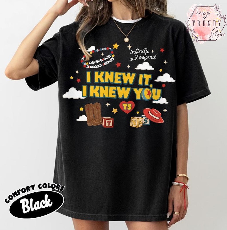 Puede incluir: Una camiseta negra con un estampado gr&aacute;fico que incluye el texto I KNEW IT, I KNEW YOU, infinity and beyond, y YOU'VE GOT A FRIEND IN ME. El dise&ntilde;o presenta ilustraciones de botas vaqueras marrones, un sombrero rojo, bloques, estrellas y nubes.