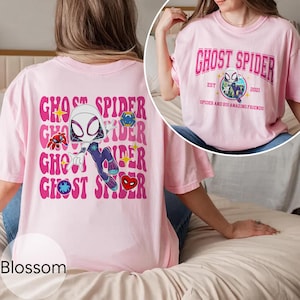 Puede incluir: Una camiseta rosa claro con el texto "GHOST SPIDER" en un dise&ntilde;o apilado y una ilustraci&oacute;n de dibujos animados de un personaje con tem&aacute;tica de ara&ntilde;a. La parte posterior de la camiseta tiene el mismo dise&ntilde;o. La parte delantera de la camiseta tiene el texto "GHOST SPIDER" con el texto "EST 2021" y "SPIDER AND HIS AMAZING FRIENDS".