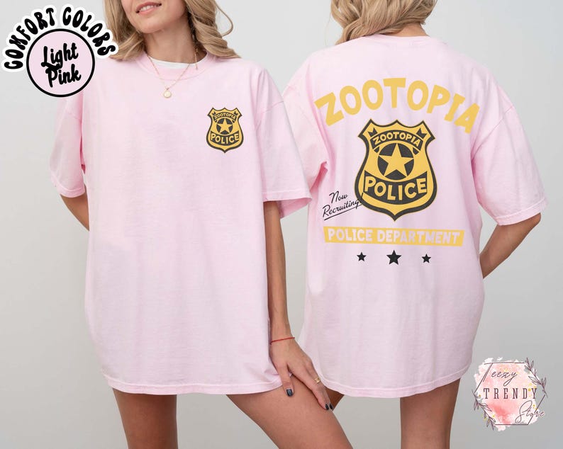 May include: Light pink t-shirt with a Zootopia Police badge on the front and back. The back of the shirt features the words "Zootopia Police Department" in yellow. The shirt is a comfort colors style.