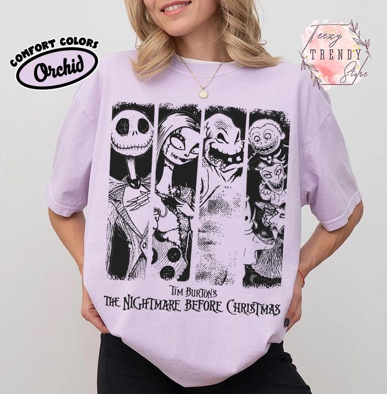 May include: A light purple t-shirt featuring a black graphic print of characters from Tim Burton's The Nightmare Before Christmas. The design includes Jack Skellington, Sally, Oogie Boogie, and other figures arranged in vertical panels with text below.