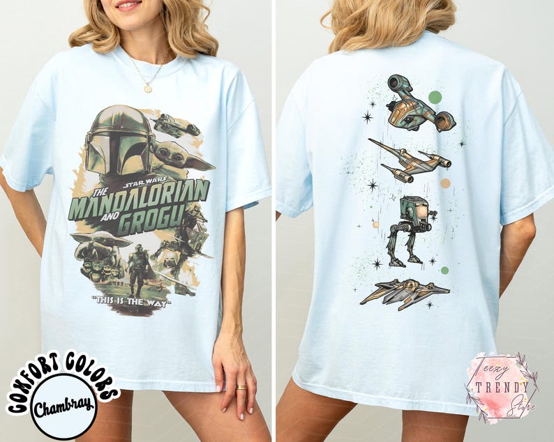 K&ouml;nnte beinhalten: Ein hellblaues T-Shirt mit einem Star Wars-Motiv auf der Vorderseite, das The Mandalorian und Grogu zeigt, inklusive des Textes The Mandalorian and Grogu und This is the Way. Die R&uuml;ckseite zeigt eine vertikale Anordnung von vier Raumfahrzeugen.