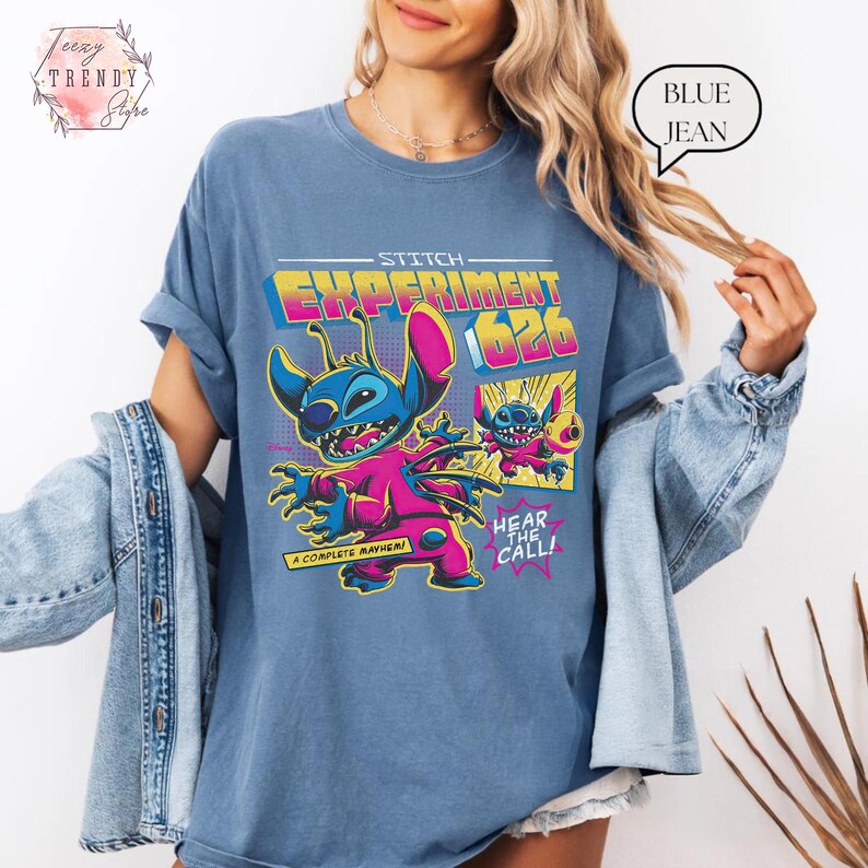 Pode incluir: T-shirt azul claro com um desenho colorido do personagem Stitch, com o texto "Experiment 626" e "Hear the Call!". O design inclui elementos rosa, amarelos e azuis. A t-shirt &eacute; de cor azul claro.