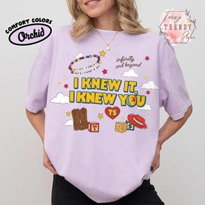 Puede incluir: Una camiseta de manga corta de color morado claro con un estampado gr&aacute;fico que incluye el texto I KNEW IT, I KNEW YOU, infinity and beyond y YOU'VE GOT A FRIEND IN ME. El dise&ntilde;o incluye botas vaqueras marrones, un sombrero rojo y estrellas.